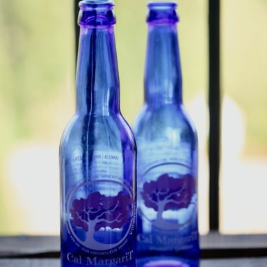 Botellas de vidrio azul con logo de árbol en el centro.